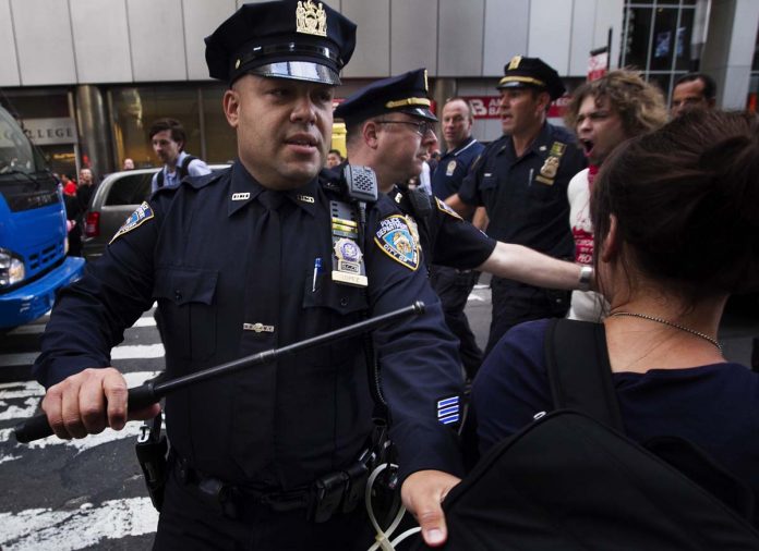An Occupy Wall Street activist is pushed off the street by a New York Police Department officer while demonstrating in the financial district during the one-year anniversary of the movement in New York