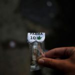 A man shows a bag with marijuana, marked C.V. for Comando Vermelho, inside a favela in Rio de Janeiro