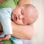 Newborn baby sleeping on her mothers arms