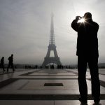 A tourist takes a picture of the Eiffel tower as he visits the Trocadero square in Paris