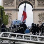 French gendarmes stand guard near barricades in front of the Arc de Triomphe during clashes with protesters on the Champs Elysees avenue after the traditional Bastille Day military parade in Paris